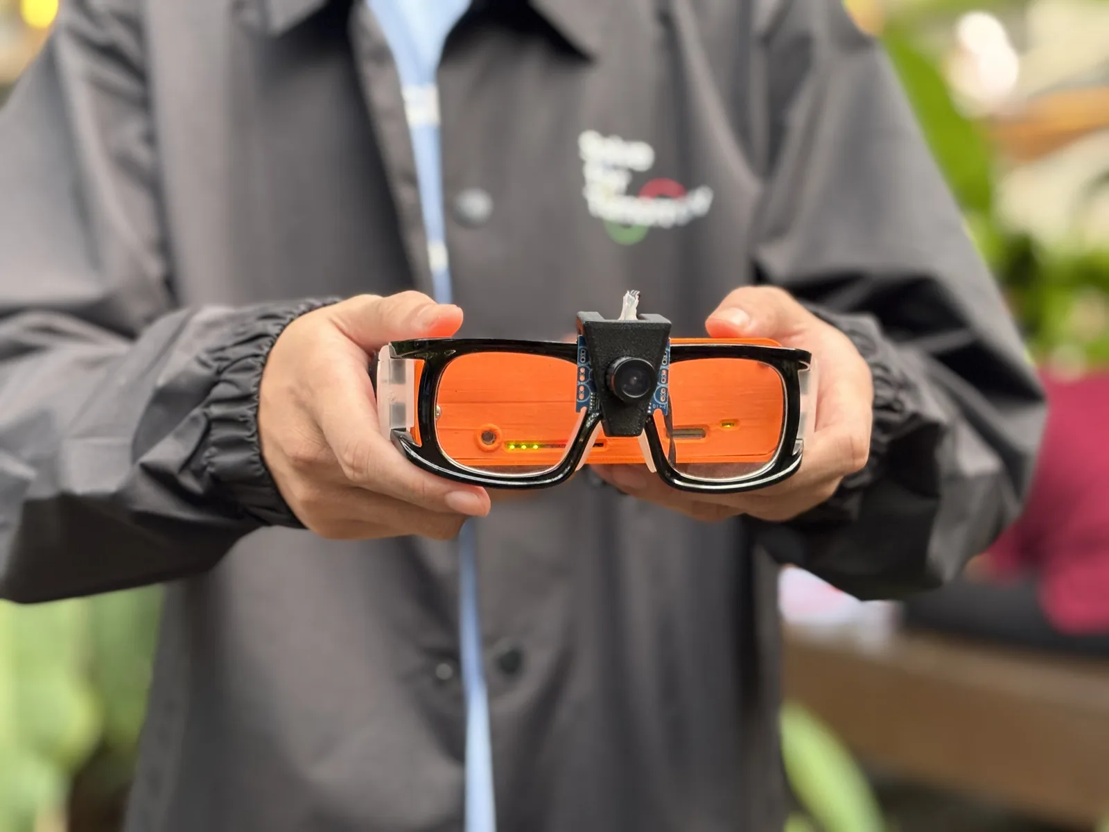 The RunSight smart glasses prototype with its camera module, held in two hands